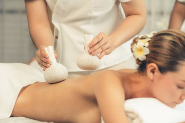 Sıcak bitkisel top spa masaj vücut tedavisi, masör kadın vücuduna nazikçe şifalı bitki torbası bastırıyor. Aromaterapi dinlenme sükuneti ve sükuneti kaplıca salonundaki atmosferi aydınlatıyor. Sessiz.
