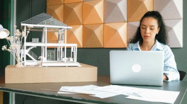 Laptop analizi ev modeli yapısını kullanan İspanyol mimar el mühendislerinin yakın çekimi. Proje yöneticisi dizüstü bilgisayarda yazarken ev modeli inşaatını kontrol ediyor. Tasarım konsepti. Yönlendirici.