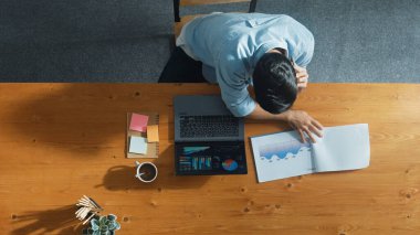 Stresli, zeki yöneticinin veri analizine bakarken dizüstü bilgisayarda çalışmasının üst hava görüntüsü. Lider, toplantı masasında karar verirken mali istatistik grafiğini belgelerle karşılaştırdı. Cemaat.