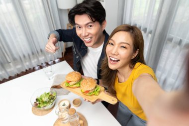 Gülümseyen ev sahibi aşçıların akıllı telefonuyla fotoğraf çekerken üst görüntüsü yemek programında çift hamburger tutarken sosyal medya kanalında ev yapımı salata tabağıyla kolaylıkla görülebiliyor. İnfobahn.