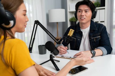 Smiling radio influencer host wearing headphone interviewing woman speaker sharing information to listeners on social media online website live streaming channel at morning at studio record. Infobahn. clipart