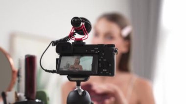 Sosyal medya için güzellik ve kozmetik video içeriği hazırlayan genç bir kadın. Güzellik blogcusu kameraya gülümserken seyircilere ve takipçilere güzellik bakımını gösteriyor. Düzenle