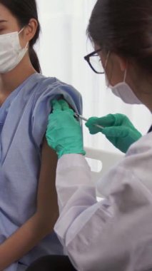 Genç bir kadın, aşı için yetenekli bir doktoru hastanede ziyaret ediyor. Covid 19 ve Coronavirus Aşı Merkezi Hizmet Konsepti .