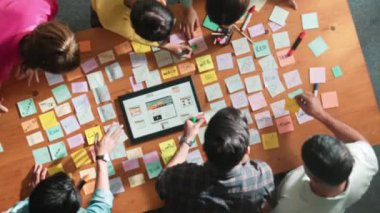 Ux Ui tasarımı kullanılarak dijital program ve yazıları tartışan ve gösteren geliştirici ekibin hava görüntüsü. İş dünyasına tepeden bakan insanlar telefon ve bilgisayar için kablo prototipi geliştiriyorlar. Sempozyum.