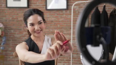 Kadın nüfuzlu kişi canlı yayın yapan video görüntülerini sosyal medya ya da blog üzerinden gözden geçiriyor. Kozmetik stüdyosu ışıklandırmalı mutlu genç kız çevrimiçi pazarlama oturumu yayını için..