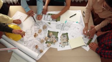 Mimari belge, ölçüm aracı ve ahşap blokların modern ofiste etrafa saçıldığı bir masa üzerinde yapı inşaatı ile ilgili mimar ve güvenlik mühendisi tartışması. Tanımlama.