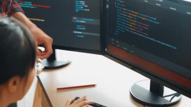 Yavaş çekimde geri uç veya yazılım geliştirici yöneticisi ekibini monitörde hata ayıklama ve karmaşık kod algoritmalarını çözmede yeni uygulama programı geliştirmede denetliyor. Filizlenen