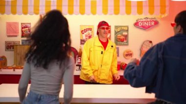 Müşteri yemek yerken garson dans edip kameraya bakıyor. Yetenekli bir restoran çalışanı, çeşitli insanlar oturup konuşurken ve şarkı söylerken hip hop müziğine canlılık katıyor. Mutluluk.