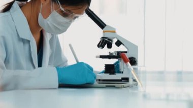 Laboratuvar kimya araştırmacısı mikroskop kullanarak yeni ilaç ya da tedavi geliştirir. Laboratuvar mikrobiyoloji ekipmanları ile bilimsel uzmanlık ile sağlık hizmetlerinin teknolojik gelişimi. Ağır çekim. Katı.