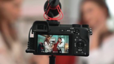 Arka görünüm, kamera ekranının arkasında iki kadın nüfuzlu görüntüleyicinin video görüntülerini, video görüntülerini, kıyafetleri, sosyal medyayı ya da blogu görüntülemesini gizler. Canlı yayın için stüdyo ışıklandırmalı kızlar canlı yayın pazarlama kayıt oturumu