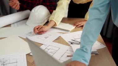 Mimarlık ve güvenlik mühendisi, modern ofiste dizüstü bilgisayarda mimari belge ve ahşap blokla sergilenen planlar hakkında tartıştı. - Yakın çekim. Tanımlama.