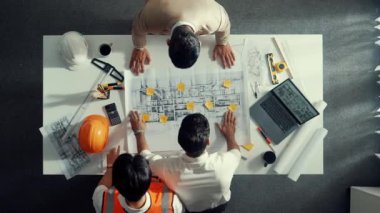 Akıllı mimar mühendis takımının yukarıdan aşağıya bakan ve bina inşaatı hakkında tartışan görüntüsü. Farklı insanlardan oluşan bir grup plan ve tasarım için birlikte çalışıyorlar. Hizalama.