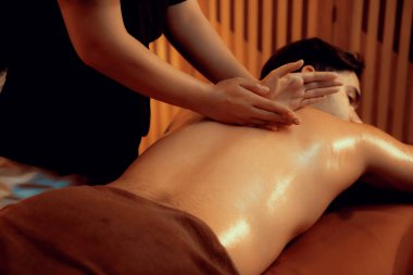 Beyaz erkek müşteri stres önleyici spa masajının keyfini çıkarıyor ve lüks otel ya da oteldeki ortam kaplıcalarında sıcak mum ışığında güzellik teniyle eğleniyor. Sessiz.