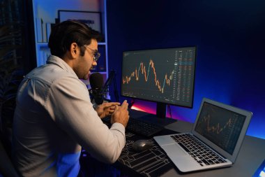 Akıllı tüccar işadamı, karanlık oda gecesinde neon ışıklı ofisteki arama pazarında yüksek kârla ekranda bilgisayar ve bilgisayar üzerinde dinamik borsa yatırımları üzerinde yoğunlaşıyor. Tahmin et..