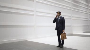 Yöneticiyle plan ve kamera hakkında konuşurken yetenekli bir yönetici yürüyor. Erkek lider, beyaz arka planda dururken satış hakkında konuşmak ve rapor vermek için iş ekibini arıyor. Sevinçli..