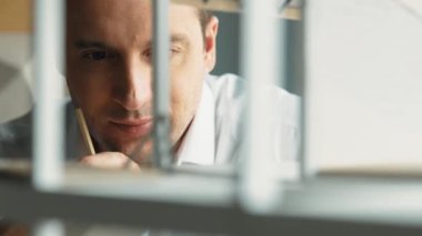 Kafkasyalı mimar mühendisinin yakın çekimi ev inşaatını denetlemek ve bina malzemelerini kontrol etmek. Proje yöneticisi modele dikkatlice bakarken kalemi işaret ediyor. Yönlendirici.