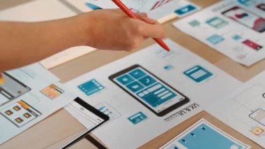 Girişimci şirket çalışanının el odaklı hali ofis çalışma alanındaki akıllı yöneticiye mobil uygulama için kullanıcı arayüzü prototipi sunar. UX UI tasarımcısı kağıt üzerinde simge tasarımının işlevini açıklıyor. Sinerjik