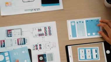 Mobil uygulama için kullanıcı arayüzü prototipini ofis çalışanlarına sunan harika bir şirket çalışanı. UX UI tasarımcısı kağıt üzerinde simge tasarımının işlevini açıklıyor. Sinerjik