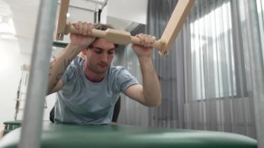 Eğitmen rehberliğinde Pilates Cadillac üzerine bar tabanlı alıştırma yapan bir müşteri. Erkek öğrenci, üst vücut gücünü arttırmak için Cadillac 'ın üzerinde kuğu esnetiyor. Alışkanlık.