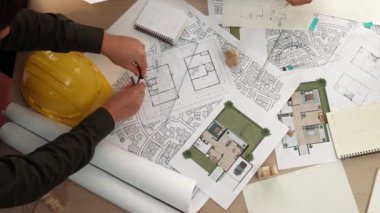 Mimari belge, ölçüm aracı ve ahşap blokların modern ofiste etrafa saçıldığı bir masa üzerinde yapı inşaatı ile ilgili mimar ve güvenlik mühendisi tartışması. Tanımlama.