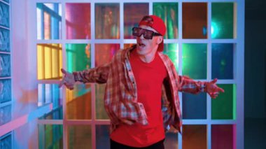 Serbest stil tişört giyerken sokak müziği çalan mutlu hipster. Gece kulübünde neon ışıkla dururken çekici break dansçı dans ve hareketli hareketler yapıyor. Mutluluk.