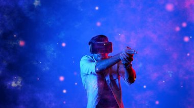 Yetenekli oyuncular silah olarak el ele tutuşup VR gözlük takıp atış oyunu oynayarak metaevrene girebiliyor. Çekici erkek model mavi arka planda dururken hareket ediyor ve oyuncuyu hedef alıyor. Aygıt.