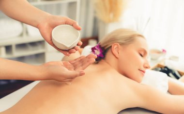 Masör elleri kadının sırtına aroma yağı döküyor. Masözler lüks otellerdeki kaplıca salonundaki müşteriler için yağ masajı prosedürü hazırlıyorlar. Aroma yağı vücut masajı konsepti. Sessiz.
