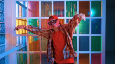 Komik break dansçı kameraya bakarken hiphop 'a doğru serbest adım atıyor. Çılgın mutlu hipster dans edip sokak dansı yaparken Led ışığında günlük kıyafet ve güneş gözlüğü takıyor. Mutluluk.