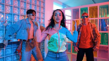 Değişik takımlarla dans ederken süslü gözlük takan yakışıklı hippi serbest stil müzikle mutlulukla dans ediyor. Beyaz hipster kulüpte parlak neon ışıkta sokak dansı yapıyor. Mutluluk.