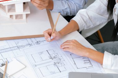 Profesyonel erkek mühendis ev modelini cetvel kullanarak ölçerken güzel bir iş arkadaşı da plan üzerinde yazarak birlikte çalışıyor. Yaratıcı tasarım ve takım çalışması. - Yakın çekim. Tertemiz..