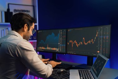 Akıllı tüccar işadamı, karanlık oda gecesinde neon ışıklı ofisteki arama pazarında yüksek kârla ekranda bilgisayar ve bilgisayar üzerinde dinamik borsa yatırımları üzerinde yoğunlaşıyor. Tahmin et..