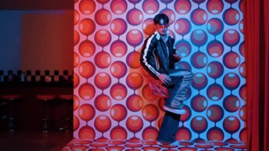 Asyalı break dansçı serbest stile geçiyor ve balon arka planlı kameraya bakıyor. Profesyonel hippi gündelik kıyafet giyer ve gözlük takar. Mutluluk.