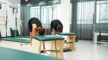 Müşteriler pilates antrenmanı sırasında ayakta gerinme egzersizi yapıyorlar. Esnekliği artırmak için. Spor salonunda bacak dayanıklılığı. Çekici grup esniyor ve eğiliyor. Alışkanlık.