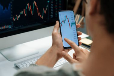 Akıllı borsa yatırımcıları ekranda akıllı telefon ile piyasa borsasını işaret ederek dizüstü bilgisayarın yanı sıra en yüksek dinamik yatırım oranını göstererek, modern işyerindeki veri planlamasına odaklanıyorlar. Bireysel.