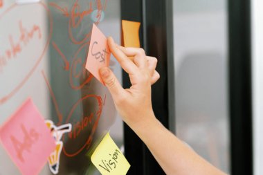 Profesyonel iş kadınının elini kapat ve iş planını sunarken renkli yapışkan notları beyaz tahtaya yapıştır. Yaratıcı iş toplantısı ve beyin fırtınası konsepti. Tertemiz..