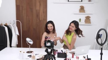 İki kadın nüfuzlu partner sosyal medya veya blog için canlı yayın yapan video klip inceleme derisi çekiyorlar. Canlı kozmetik stüdyo ışığı olan genç bir kız çevrimiçi pazarlama kayıt oturumu yayını için.