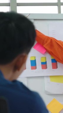 Genç bir kadın günlük ofis odasındaki beyaz tahtadaki iş verilerini açıklıyor. Kendine güvenen Asyalı işkadını, pazar stratejisini belirlemek için ortak olarak yürütülen bir iş projesinin bilgi ilerlemesini rapor etti .