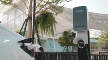 Green City Park 'taki otoparkta yavaş çekim EV elektrikli araba şarj bataryası. Sürdürülebilir ve çevre dostu şehir yolculuğu için yenilenebilir otomobil için alternatif temiz enerji teknolojisi. Yararlı