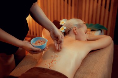 Lüks spa salonlarında sıcak mum ışığında cilt bakımı yaptıran kadın müşteri. Sağlık Spa vücut fırçasında tuz temizleme güzellik tedavisi. Sessiz.