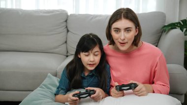 Kafkas anne ve kızı oturma odasında oturup oyun oynuyorlar. Mutlu anne, elinde joystick tutarken akıllı Asyalı kızla vakit geçiriyor. Oyun oynamaktan zevk alıyor. Yaşam tarzı konsepti. Pedagoji.