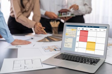 İç mimar tasarımcı grubu, daha kesin tasarım için planlar ve dizüstü bilgisayar ekran mimari yazılımı üzerinde birlikte tartışıyorlar. Modern ev tasarımı ve yenileme. İçgörü