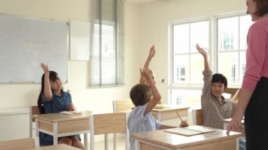 Çeşitli zeki öğrenciler sınıfta çalışırken ve mutlu öğretmenleri dinlerken soruları cevaplamak için ellerini kaldırdılar. Çok kültürlü çocuklar gönüllü oldular, oy verdiler, soru sordular. Pedagoji.