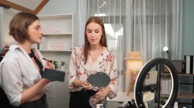 Etkilenen iki ortak canlı yayında video görüntülerini çekiyor makyaj malzemesi prim sosyal medya veya blog. Kozmetik stüdyosu ışıklandırmalı mutlu genç kız çevrimiçi pazarlama oturumu yayını için..