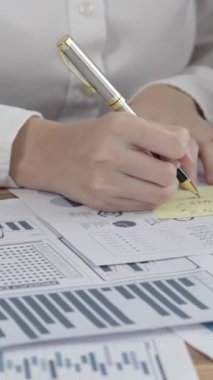 Ofis masasında çalışan iki hevesli genç iş kadını, veri tablosu raporlarıyla birlikte. Genç meslektaşlar istatistik veri kağıdı planları ve stratejisini tartışıyor ve analiz ediyorlar.