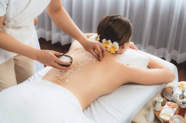 Lüks spa salonlarında sıcak mum ışığında cilt bakımı yaptıran kadın müşteri. Sağlık Spa vücut fırçasında tuz temizleme güzellik tedavisi. Sessiz.