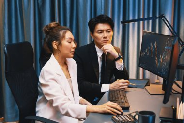 Gülümseyen Asyalı tüccarlar dinamik borsa verilerine işaret ediyor. Gece vakti internet sitesinde kar etme programı. Veri raporunda para birimi değeri analiz ediliyor. İnfobahn.