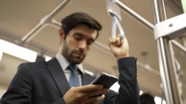 İş adamının elleri trende insanlarla çevriliyken telefona bakarken yakın çekim. Kafkas proje yöneticisi e-postaları kontrol ediyor, arka planı bulanık pazarlama stratejisi planlıyor. Sevinçli..