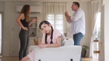 Sinirli ve mutsuz genç bir kız oturma odasında ebeveyninin tartışması yüzünden gerginliğin ortasında kanepede oturuyor. Sağlıksız ev hayatı ve travmatik çocukluk depresyona dönüşür.