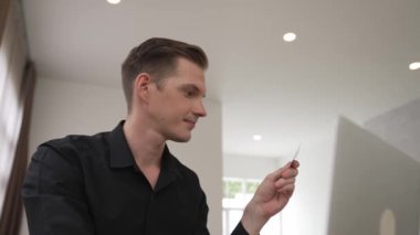 Genç adam internet bankacılığı için kredi kartlı dizüstü bilgisayar kullanıyor. İnternet üzerinden alışveriş yapıyor. Banka kartıyla modern ve kullanışlı online satın alma. Düzenle