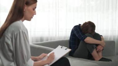 Psikologla ruh sağlığı terapisi gören üzgün travma sonrası stres bozukluğu olan bir kadın. Yaşam sonrası depresyon veya keder. Hayal kırıklığına uğramış genç bir kadın klinikteki duygular hakkında prim psikoloğuyla konuşuyor.